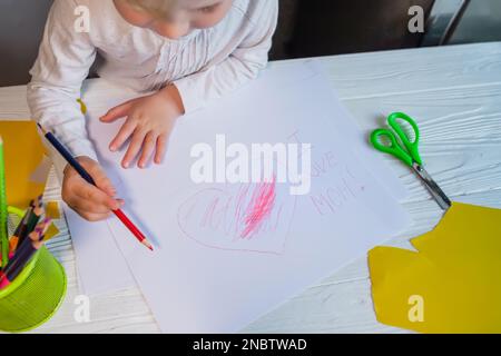 Scheda del giorno della mamma. Il bambino ha disegnato un cuore e ha scritto che amo mia madre. Foto Stock