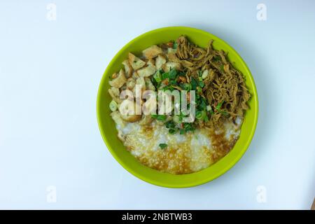 Una ciotola di porridge di pollo (bubur ayam) è cibo per colazione indonesiano Foto Stock