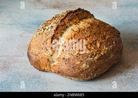 Pane fresco a grana intera con semi di lino, farinata d'avena, semi di sesamo su sfondo colorato, concetto di cibo sano. Foto Stock