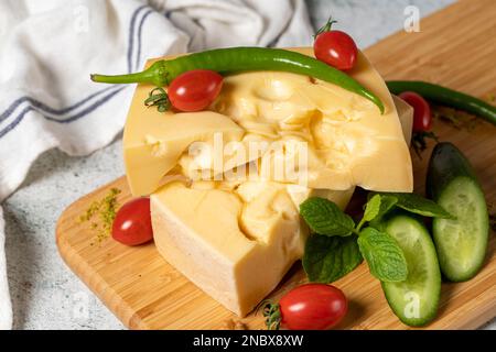 Formaggio Gruyere. Pezzo di formaggio Gruyere su tagliere di legno. Raccolta di formaggi Foto Stock