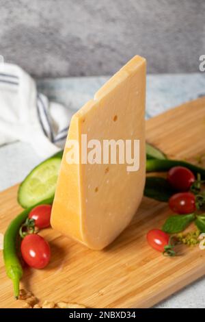 Formaggio Gouda. Pezzo di formaggio gouda su tagliere di legno. Raccolta di formaggi. Formaggio stagionato a base di latte vaccino nei Paesi Bassi Foto Stock