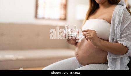 Sezione mediana della donna incinta di prendere la medicina a casa Foto Stock