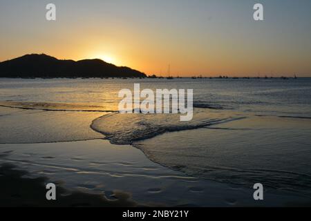 Ondate sulla spiaggia coperta d'acqua a Playa Coco, Costa Rica, al tramonto Foto Stock