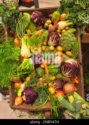 Verdure diverse in una scatola di legno o vendita in un stand di vendita. Immagine ravvicinata. Foto Stock