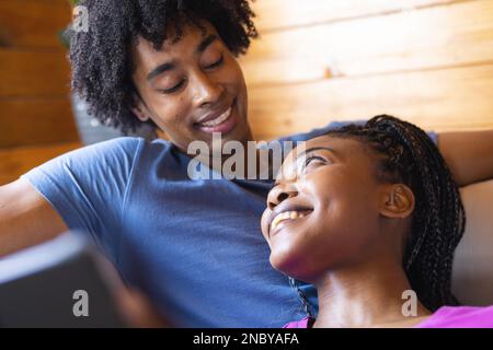 Coppia afro-americana felice che passa il tempo nella cabina del ceppo che si trova. Cabina di legno, natura e concetto di stile di vita. Foto Stock