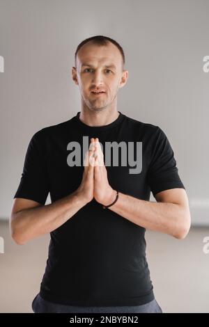 Un uomo di costruzione atletica fa yoga in palestra su un tappetino. Foto Stock