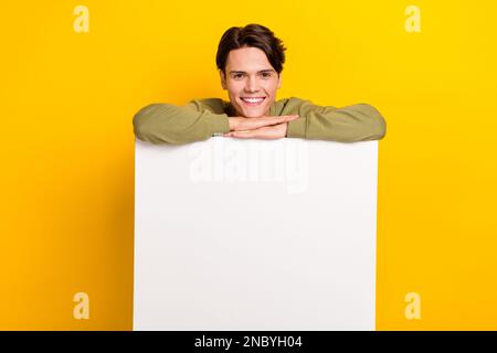 Foto di positivo uomo di successo indossare abiti cachi stand dietro la tavola spazio vuoto promuovere negozio isolato su sfondo di colore giallo Foto Stock