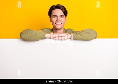 Foto di allegro bel uomo indossare abiti eleganti stand dietro parete bianca presentando spazio vuoto isolato su sfondo di colore giallo Foto Stock