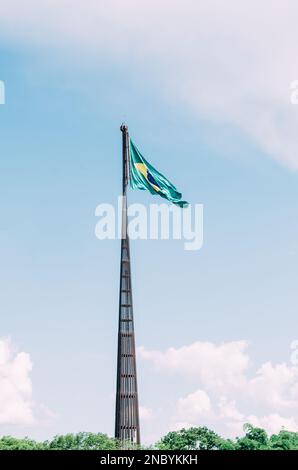 Bandiera brasiliana che vola, svolazzando nel vento e con il cielo blu sullo sfondo. Foto Stock