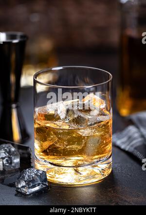 Bicchiere di whisky con bevanda ghiacciata su fondo di legno scuro Foto Stock