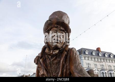 Il lungomare di Llandudno, Galles del Nord, Regno Unito con la statua in legno di Mad Hatter in primo piano Foto Stock