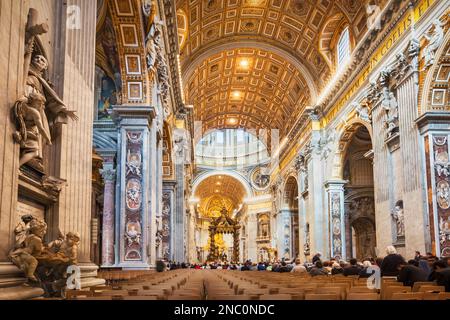 La gente partecipa a una messa nella Basilica di San Pietro in Vaticano Foto Stock