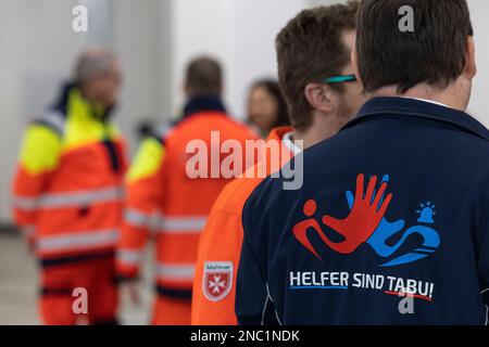 Magonza, Germania. 14th Feb, 2023. I paramedici si trovano durante un incontro con il Ministro Presidente della Renania-Palatinato presso la stazione di soccorso della Croce Rossa tedesca (DRK) a Magonza. Una persona indossa una felpa dell'associazione "Helpers are off limits", che mira a sostenere gli aiutanti e a scoraggiare i trasgressori. Dreyer e il suo Ministro dell'interno sono venuti anche alla stazione di soccorso per parlare con i paramedici di emergenza delle loro esperienze con ostilità e aggressioni sul campo. Credit: Hannes P. Albert/dpa/Alamy Live News Foto Stock