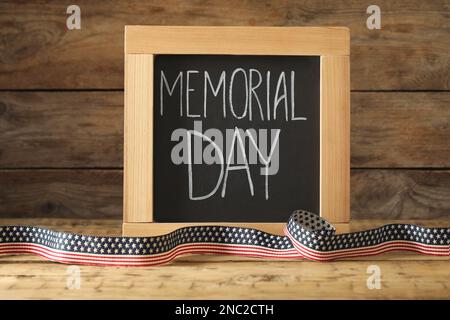 Lavagna con frase Memorial Day e nastro su tavolo di legno Foto Stock