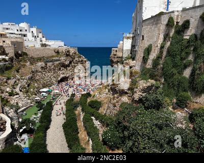 I bagnanti possono godersi la spiaggia di Lido Cala Paura a Polignano a Mare. Circondato da scogliere drammatiche e acque cristalline del Mare Adriatico, è Foto Stock