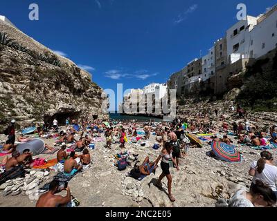 I bagnanti possono godersi la spiaggia di Lido Cala Paura a Polignano a Mare. Circondato da scogliere drammatiche e acque cristalline del Mare Adriatico, è Foto Stock