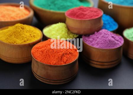 Polveri colorate in ciotole di legno su sfondo nero. Festa di Holi celebrazione Foto Stock