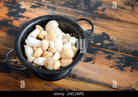 Funghi Eringi o Re Trumpet freschi crudi su un tavolo di legno. Foto Stock