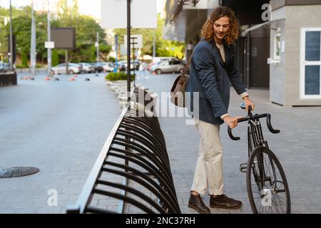 Zenzero europeo che indossa una giacca a piedi con la bicicletta sulla strada cittadina Foto Stock