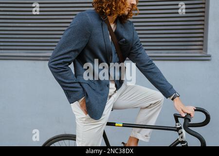 Zenzero europeo che indossa una giacca in bicicletta in strada cittadina Foto Stock