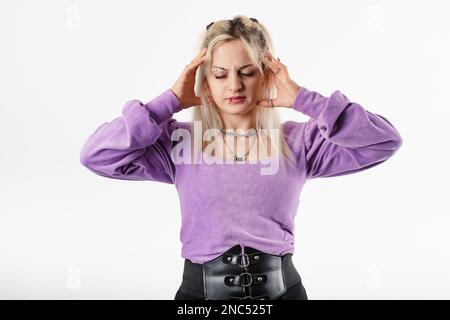 Ritratto di donna bionda con blusa a coste in piedi isolato su sfondo bianco che soffre di mal di testa disperato e stressato perché dolore e. Foto Stock