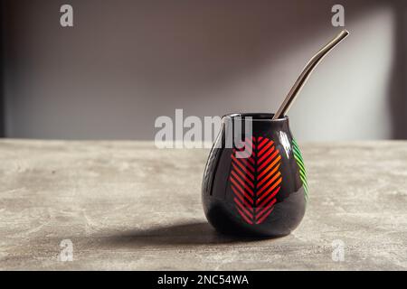 tazza di yerba mate in ceramica piuttosto lucida, con design a foglia rossa e paglia di metallo bombarbilla Foto Stock