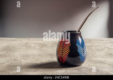 tazza di yerba mate in ceramica piuttosto lucida, con design a foglia arancione e blu e paglia di metallo bombarbilla Foto Stock