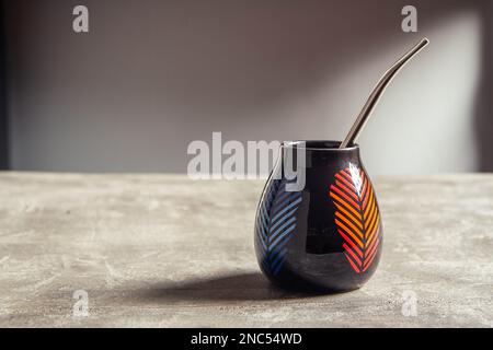 tazza di yerba mate in ceramica piuttosto lucida, con design a foglia arancione e blu e paglia di metallo bombarbilla Foto Stock