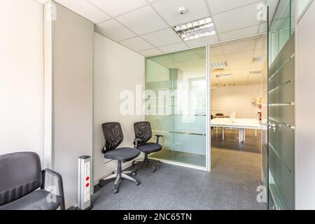 Edificio abbandonato di un proprietario insolvente con un interno in un semplice stile ufficio. Uffici, a sinistra e a destra, con divisori in vetro e un piccolo sole Foto Stock