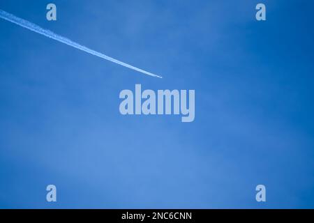 il motore gemello ad alta quota contrasta (piste di vapore di aerei a reazione) attraverso un cielo blu profondo e chiaro Foto Stock