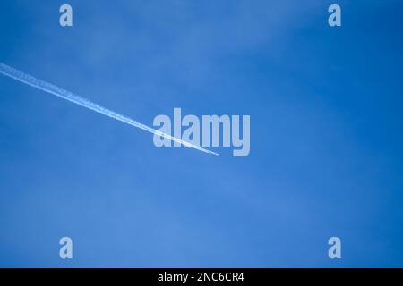 il motore gemello ad alta quota contrasta (piste di vapore di aerei a reazione) attraverso un cielo blu profondo e chiaro Foto Stock