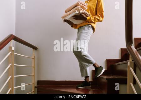 Donna che trasporta una pila di asciugamani freschi alla camera da letto degli ospiti Foto Stock