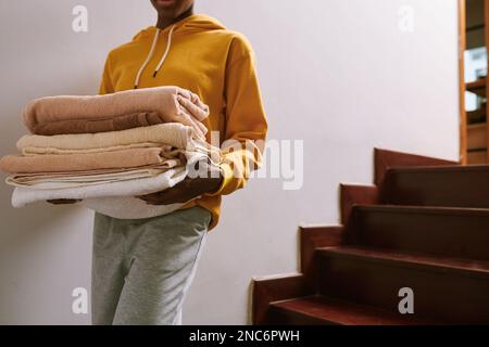 Donna che trasporta gli asciugamani freschi puliti e soffici al bagno Foto Stock