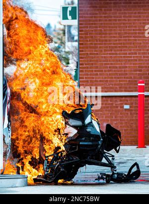 Motoslitta nera in fiamme presso una stazione di servizio con enormi fiamme Foto Stock