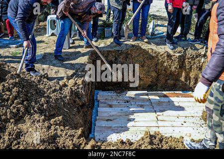 Hatay, Turchia. 14th Feb, 2023. Le persone gettano terra sulla tomba durante la sepoltura. Una famiglia seppellì i loro 3 figli che furono persi nel terremoto. (Foto di Murat Kocabas/SOPA Images/Sipa USA) Credit: Sipa USA/Alamy Live News Foto Stock