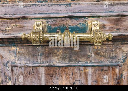 maniglia in ottone antico su una vecchia porta in legno con vernice appena rimossa Foto Stock