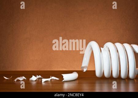 Una lampadina CFL fluorescente compatta rotta si è frantumata in frammenti di vetro Foto Stock