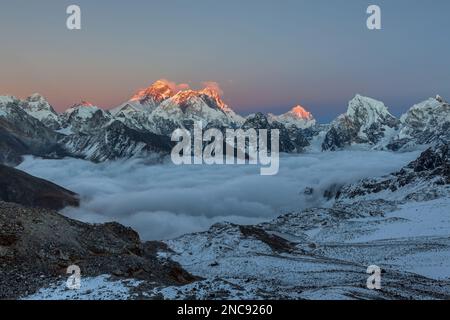 Tramonto sulla cima dell'Everest, vista dal passo di Renjo la. Vista mozzafiato della valle di montagna coperta da nuvole ricci. Spettacolare vetta innevata dell'Everest ri Foto Stock