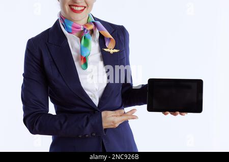 Primo piano su elegante hostess aria femminile isolato su sfondo bianco in uniforme che mostra lo schermo vuoto del PC tablet. Foto Stock