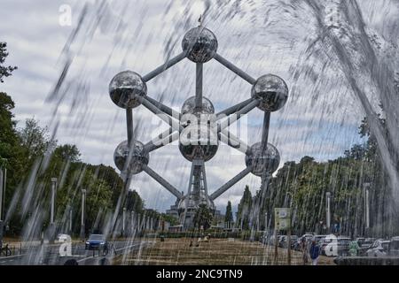 Monumento dell'Atomium, con una fontana in primo piano. Scattato contro un cielo nuvoloso. Bruxelles, Belgio.. Foto Stock