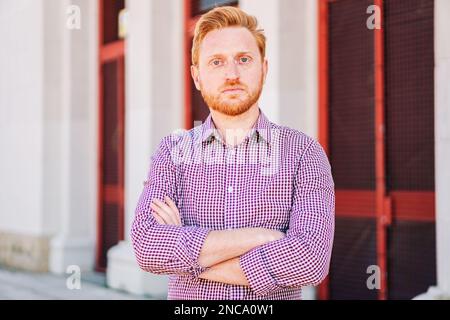 Serious Redhead Man che guarda la telecamera in piedi all'aperto. Primo piano Ritratto di un giovane triste. foto di alta qualità Foto Stock
