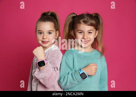 Bambine con orologi intelligenti su sfondo rosa Foto Stock