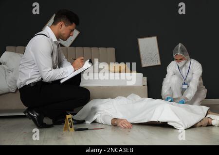 Investigatori che lavorano sulla scena del crimine con il corpo morto Foto Stock