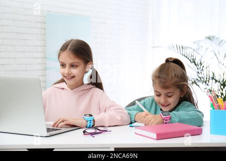 Bambine con eleganti orologi eleganti al tavolo al chiuso Foto Stock