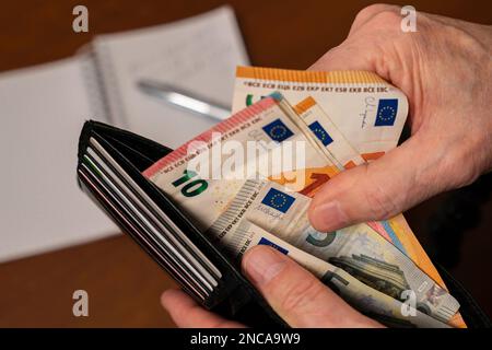 Primo piano delle mani di un uomo che conta denaro in una borsa. Foto Stock