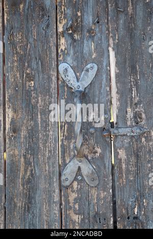 porta in legno color pastello grigio con maniglia in argento metallico decorativa a forma di hart strisce verticali, porte aperte e chiuse Foto Stock