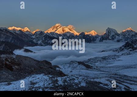 Bellissimo tramonto sulla cima dell'Everest, vista dal passo di Renjo la. Splendida vista sulla valle di montagna coperta da nuvole ricci. Spettacolare vetta innevata di Evere Foto Stock