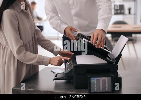 Dipendenti che utilizzano una stampante moderna in ufficio, in primo piano Foto Stock
