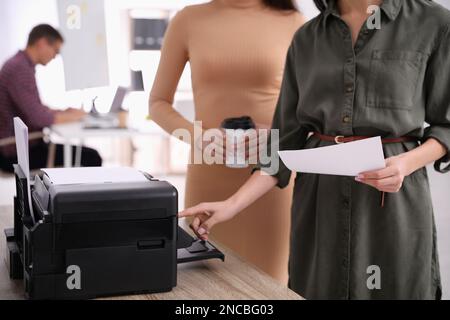 Dipendenti che utilizzano una stampante moderna in ufficio, in primo piano Foto Stock