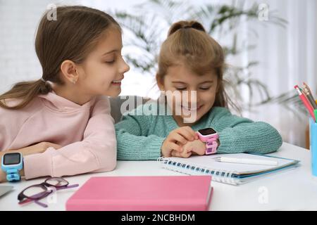 Bambine con eleganti orologi eleganti al tavolo al chiuso Foto Stock